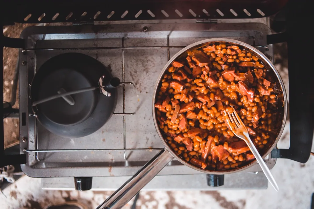 A pan of beans simmering with tomato and a fork resting in it