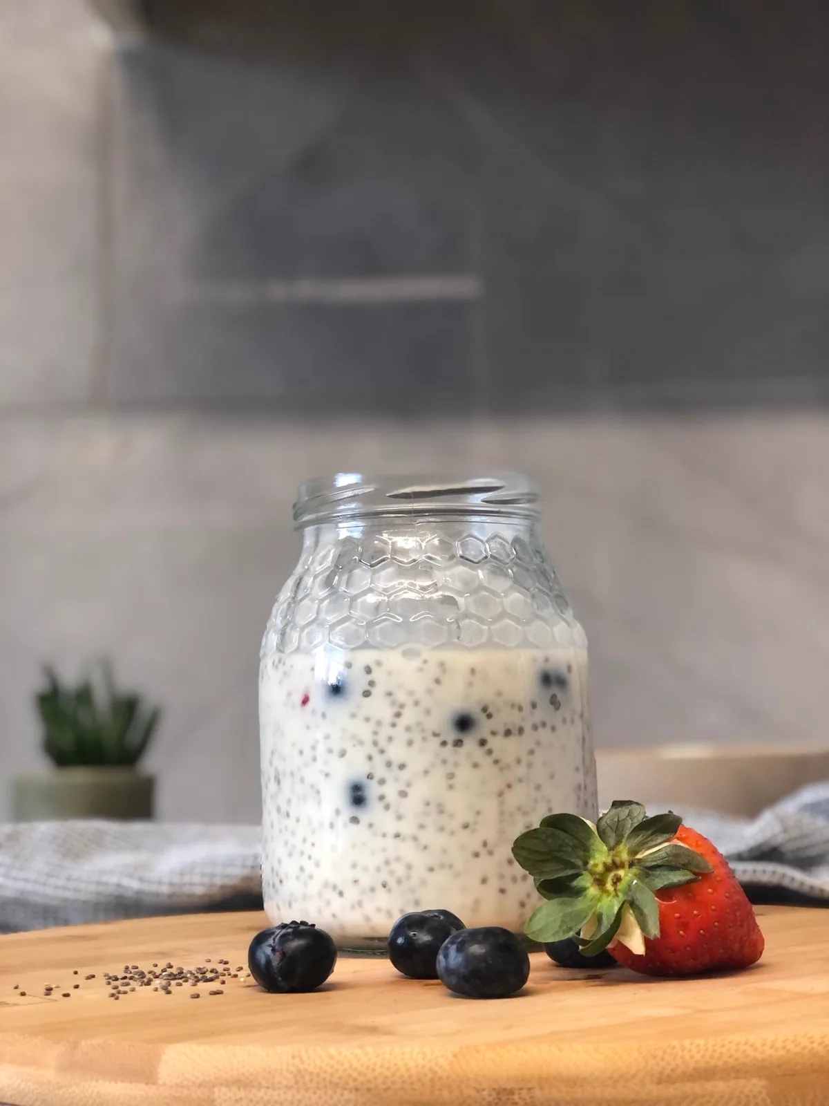 A glass jar of chia and oat pudding topped with berries