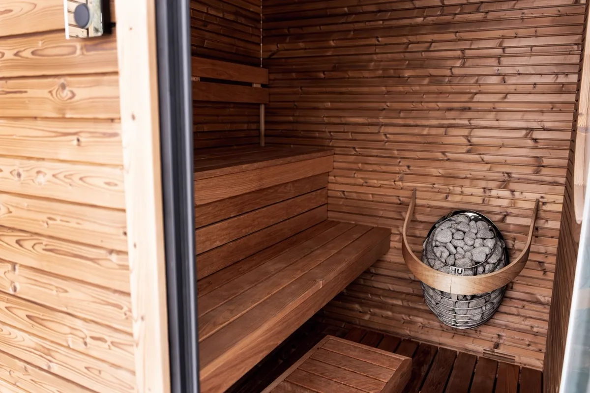 A wood-lined sauna with a stone-topped electric heater and bench seating