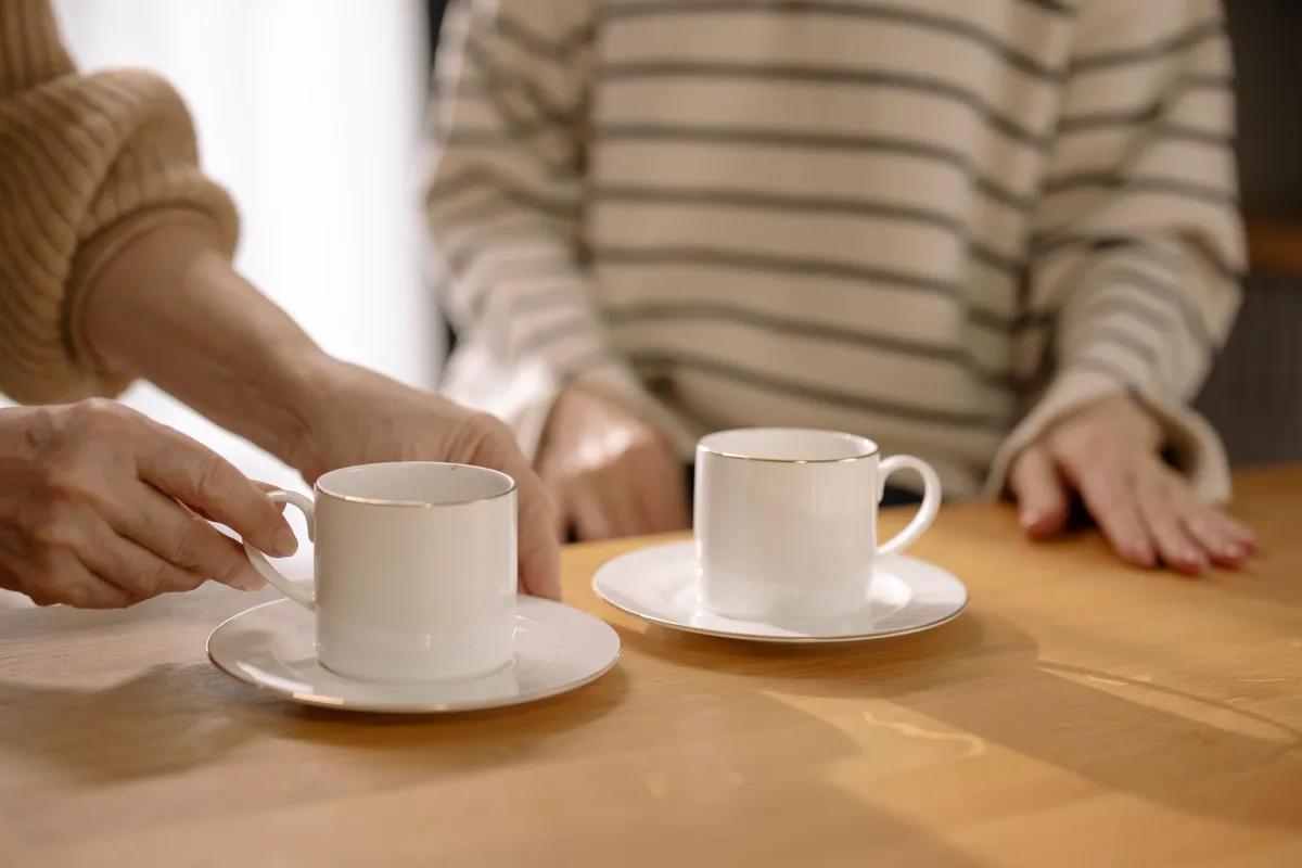 Two cups of coffee on a wooden table in warm morning light