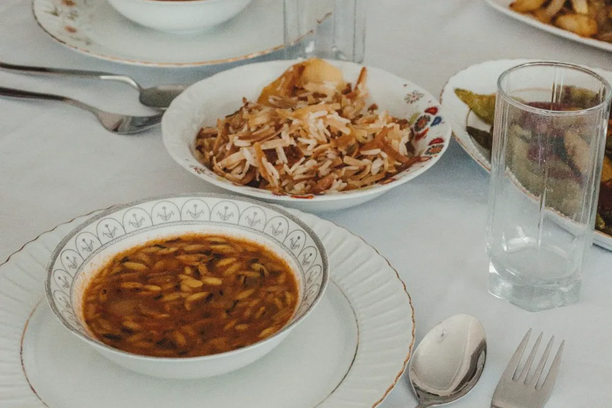 A plate of home-cooked food and a bowl of soup on a kitchen table, part-eaten